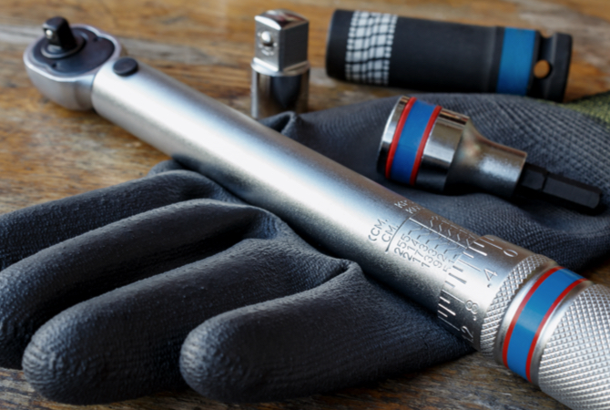 Torque wrench resting across a work glove with a flashlight and socket in the background.