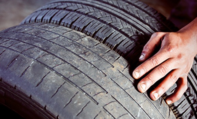 wheel-and-tire-problems Close up on a tire, specifically tire tread, with a mechanic inspecting it