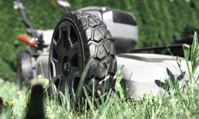 lawn-mower-mowing-grass Close up of lawn mower mowing through grass.