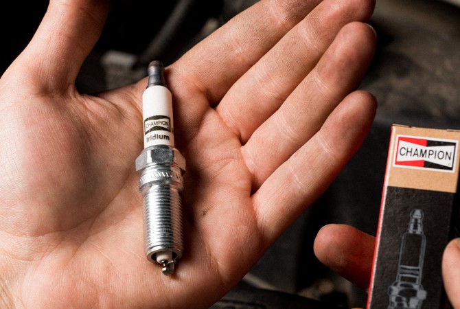 mechanic-holding-champion-spark-plug Hand holding a spark plug