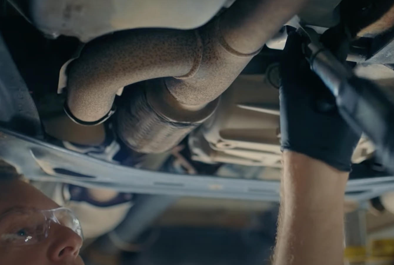 Mechanic installing oil pan on vehicle 