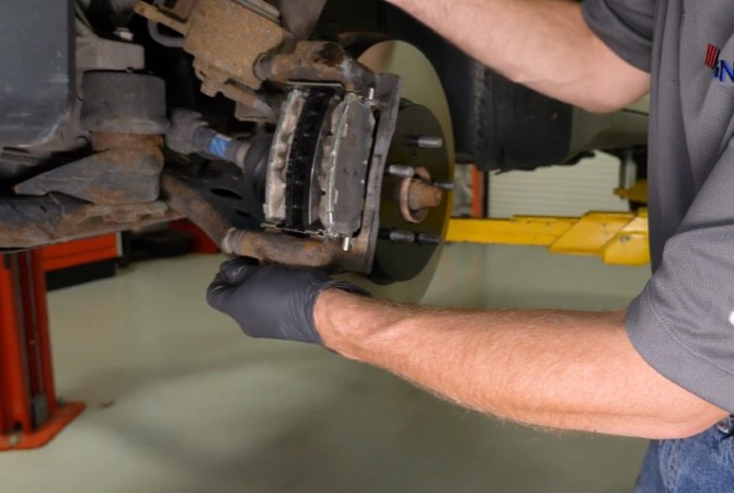 how-to-do-complete-brake-job-step-9 Technician installing brake caliper assembly