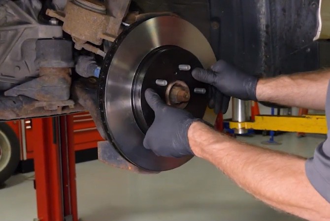how-to-do-complete-brake-job-step-6 Technician installing brake rotor