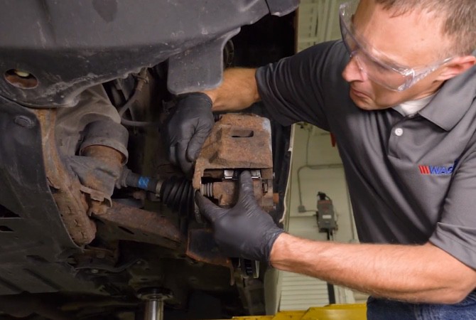 how-to-do-complete-brake-job-step-1 Technician pushing brake caliper back on