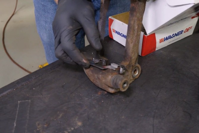 how-to-do-complete-brake-job-step-7 Technician installing new brake caliper hardware