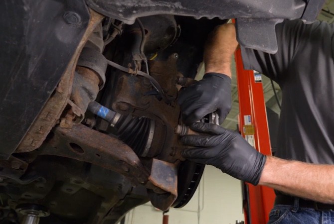 how-to-do-complete-brake-job-step-10 Technician pushing brake pads against rotor